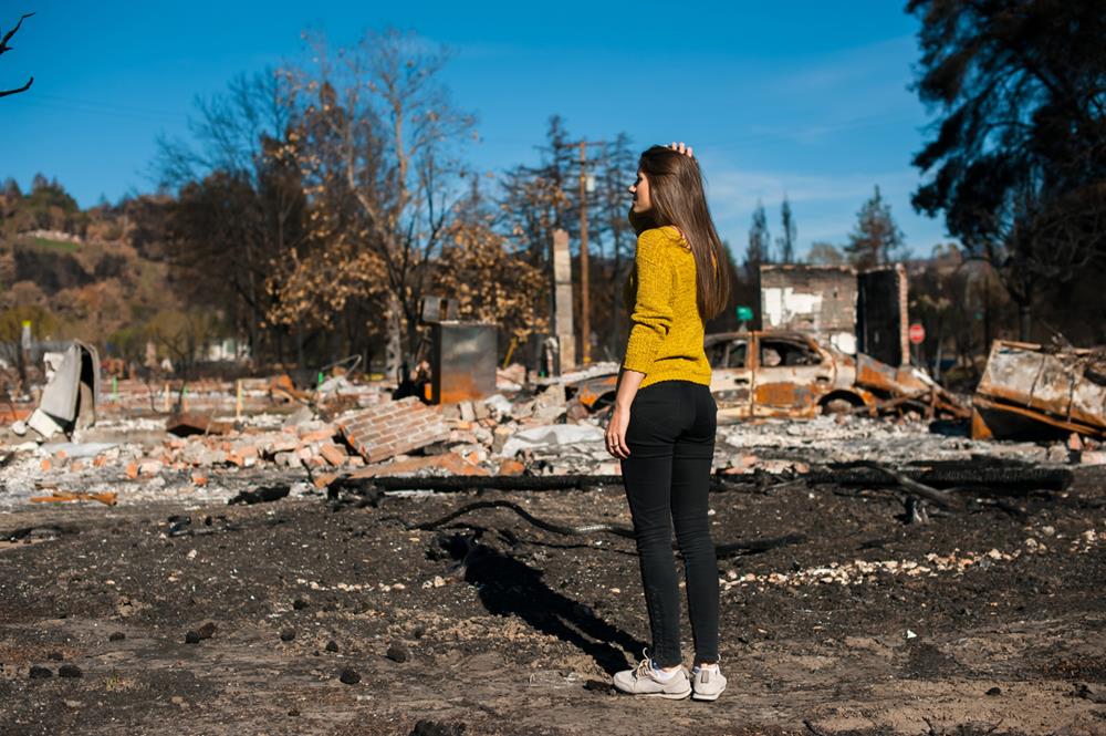 Woman checking burned and ruined house and yard after fire