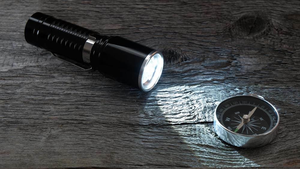 Flashlight and compass on a table
