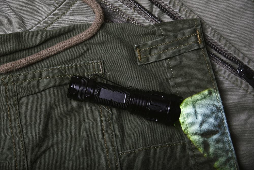 Tactical flashlight on green army jacket