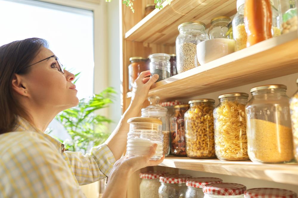 Woman checking jars of grains in pantry