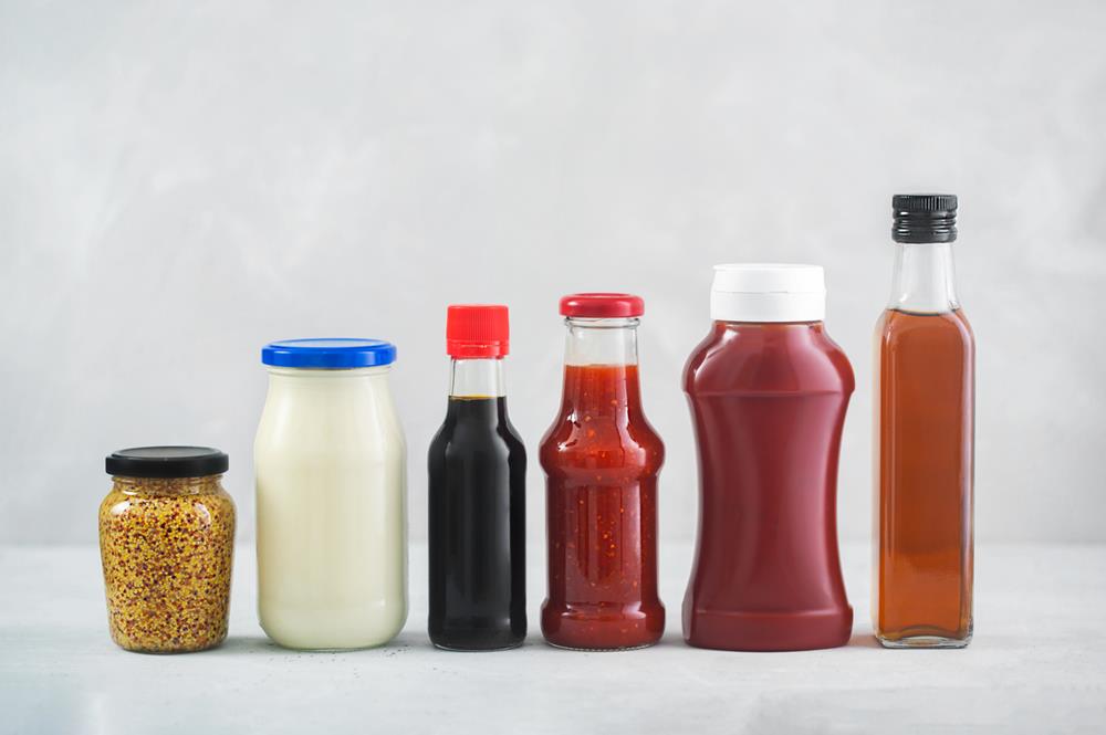 Different condiments in jars and bottles