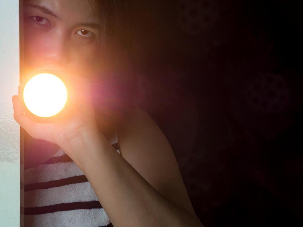 Woman holds the flashlight by the door