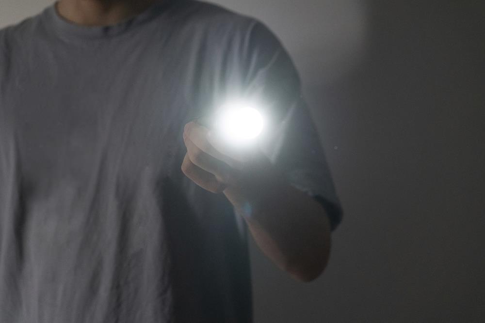 Holding an electric light torch in the dark space