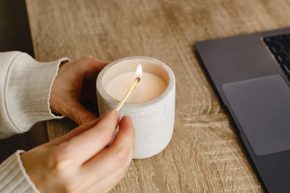 Girl lights a candle at her desk at home
