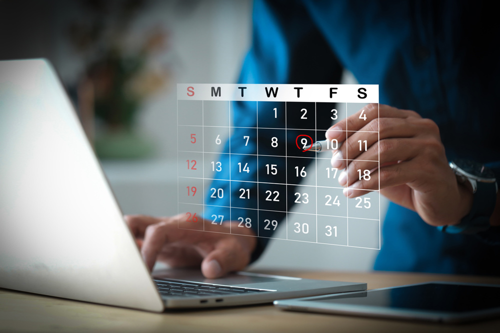 Businessman hands using laptop computer with virtual calendar interface for appointment scheduling