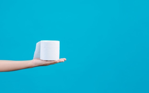 Girl wearing white pajamas and holding a roll of tissue paper