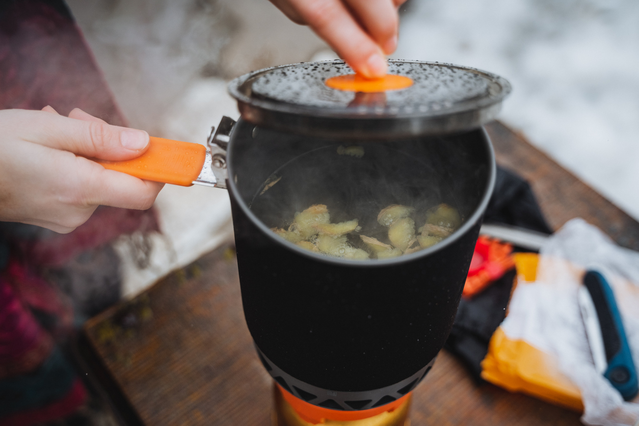cooking in a pot on a gas burner in a campsite, hiking in the forest, cooking on a hike, trekking in the mountains.