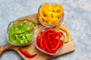 Red, green, and yellow capsicums in spice bowls
