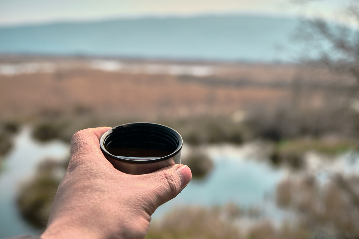 a hand holding a coffee mug outdoors