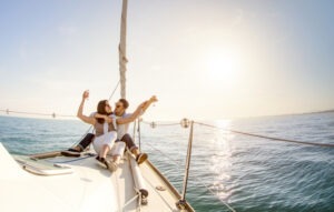 Young couple in love on sail boat with champagne at sunset - Happy people lifestyle on exclusive luxury concept - Soft backlight focus on warm afternoon sunshine filter - Fisheye lens distortion